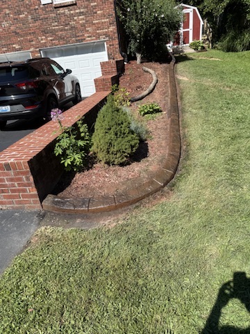 A sweeping decorative curb along the side of a brick home and driveway