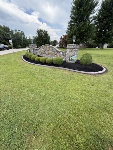 Neighborhood entrance with fresh mulch and a continuous decorative border