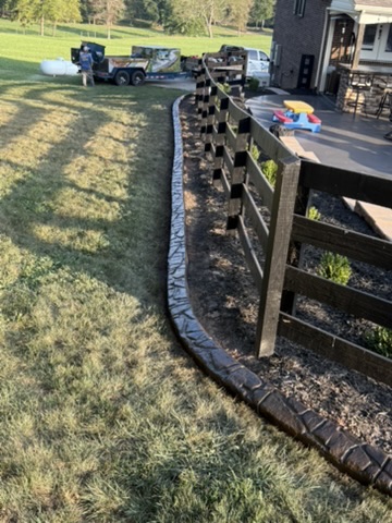 Decorative curbing follows a black fence