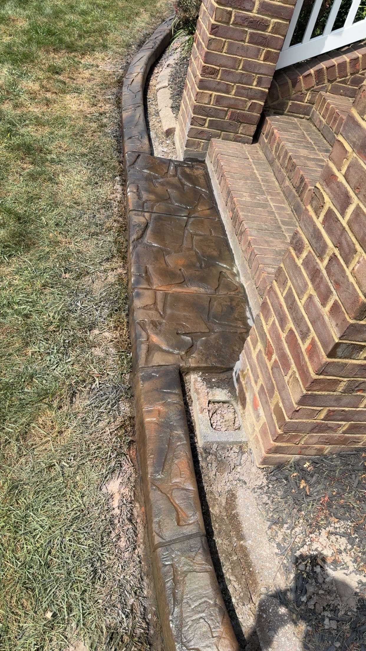 Finished stamped concrete and curbing beside the same brick steps