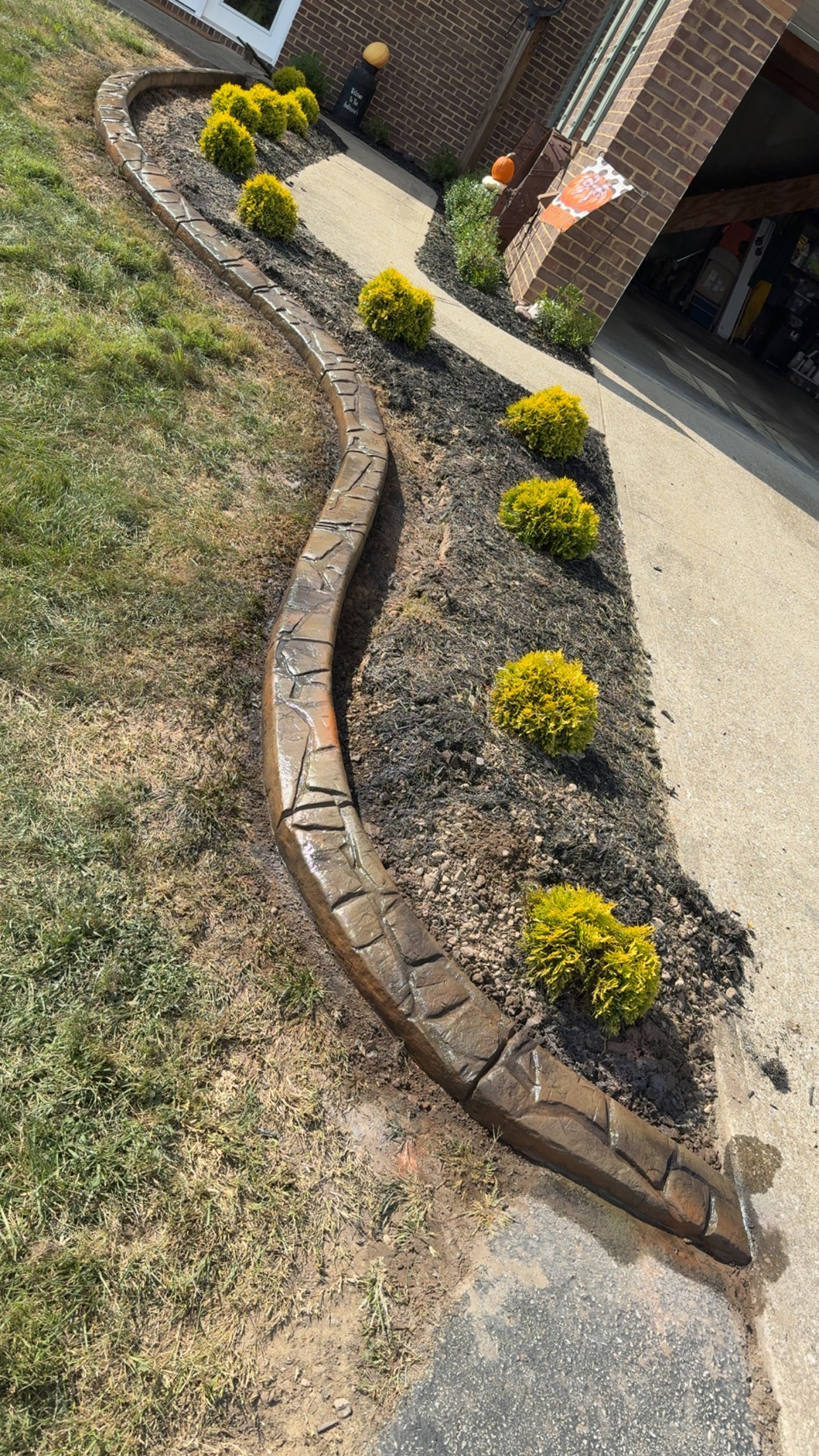 Decorative curbing curves along a garden beside a brick home